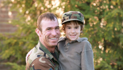 Veteran in uniform holding child.