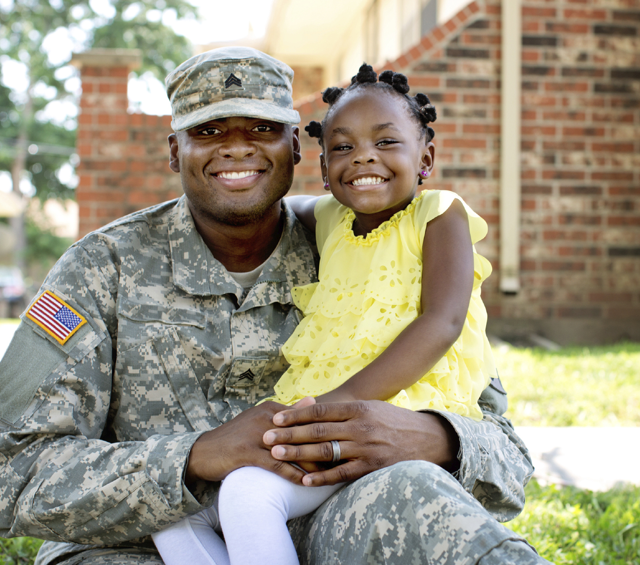 Veteran wears uniform and holds smiling daughter.