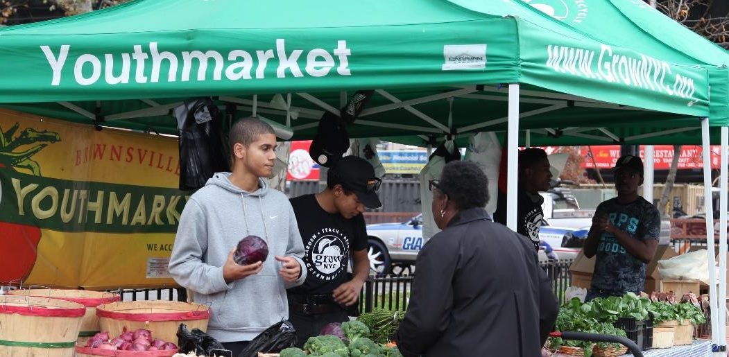 Community members buy vegetables at healthy food stands.
