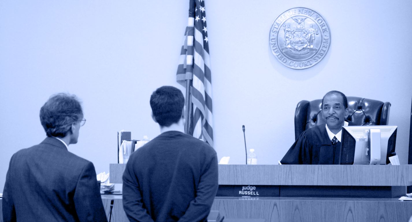 Two men speak with the judge at a courthouse.