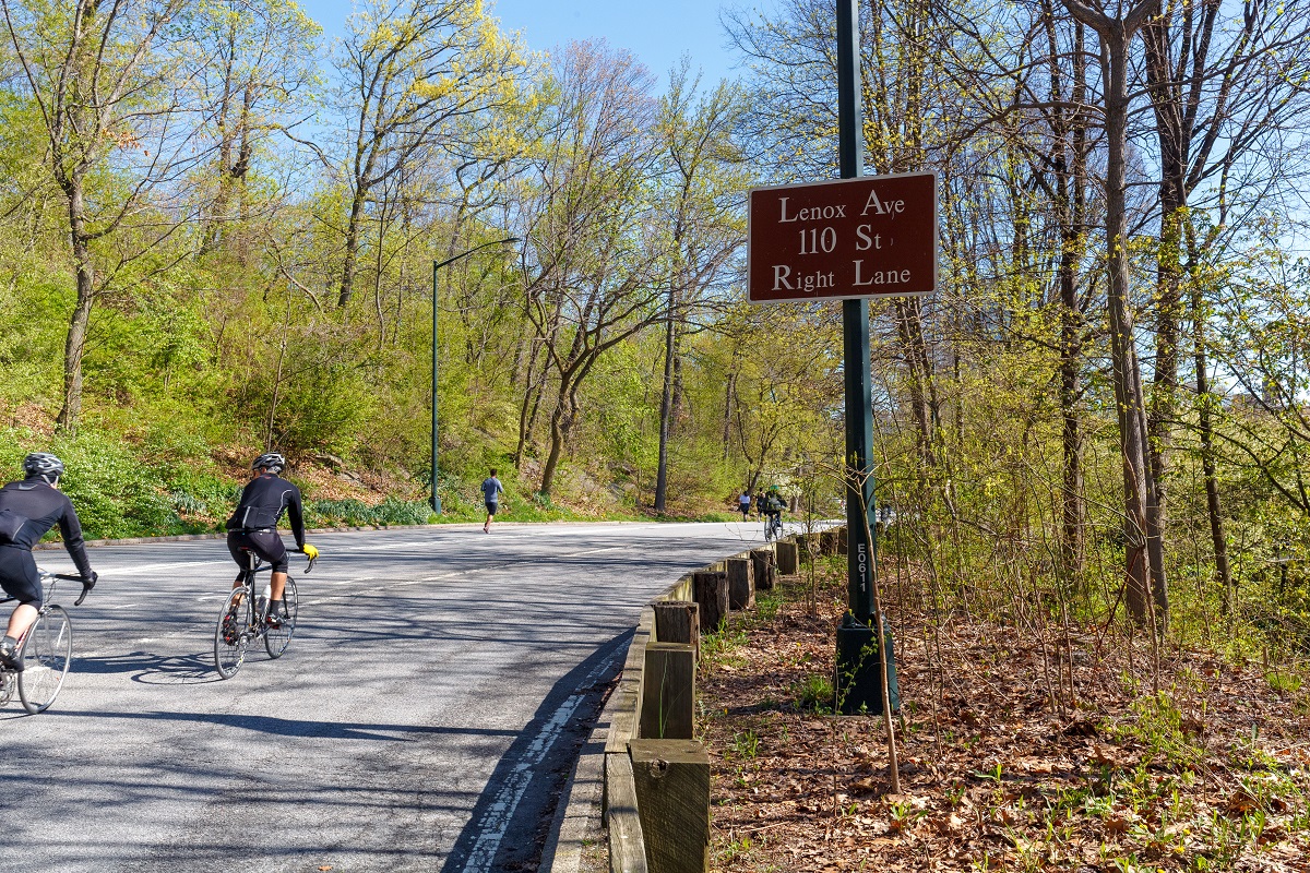 Bikers and runners on a trail in East Harlemt with the sign post that says 