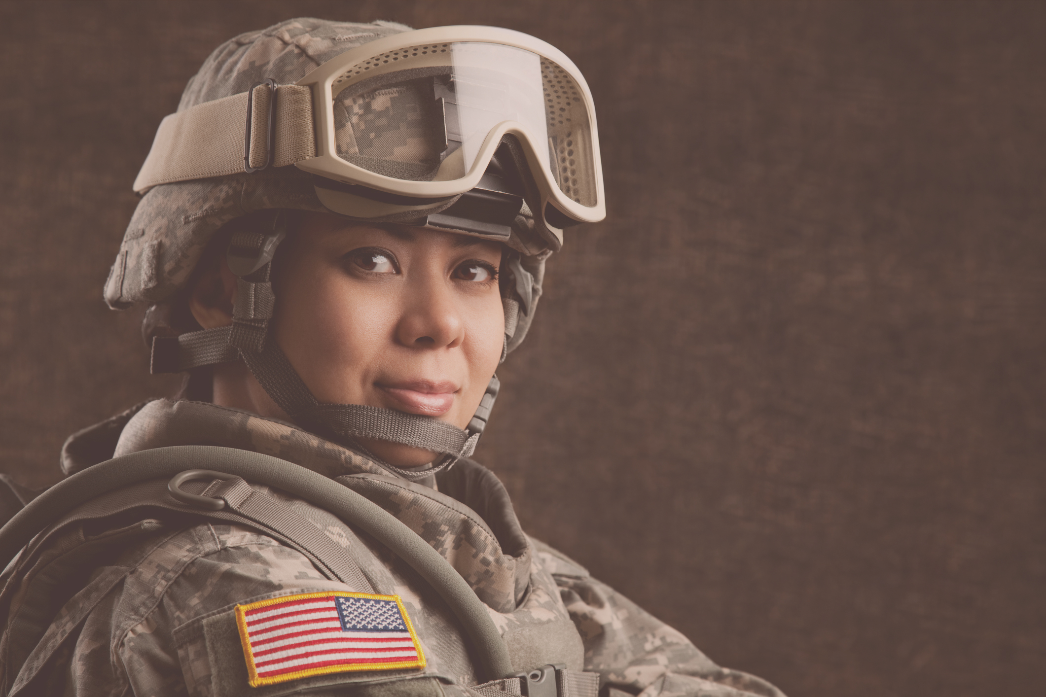 A woman veteran in military camo fatigues looks directly at the camera.