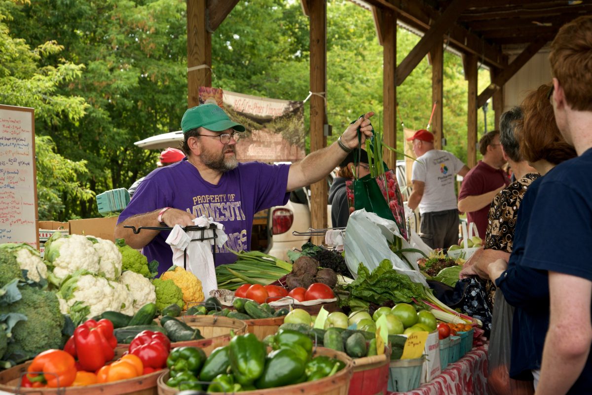 Worker assists customers at healthy fruit and vegetable stand.