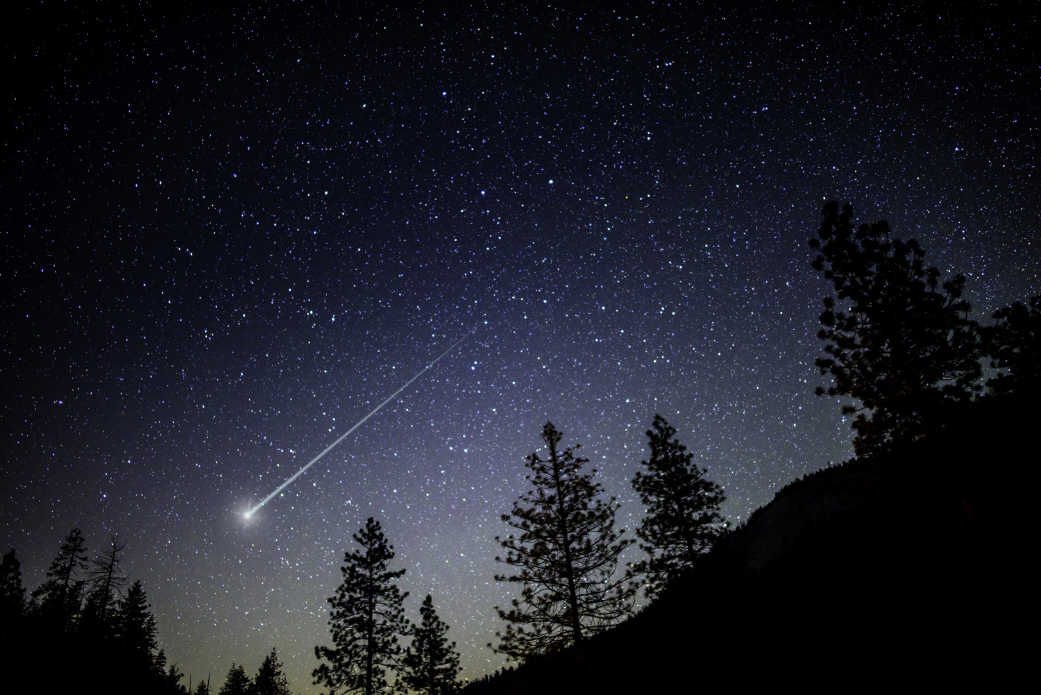 Night sky with a shooting star passing by.