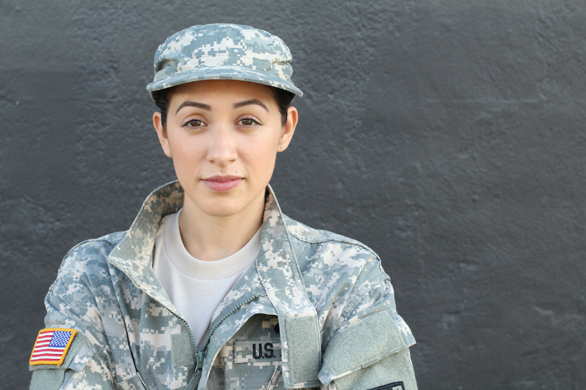 A U.S. military veteran in fatigues faces the camera with a neutral expression.