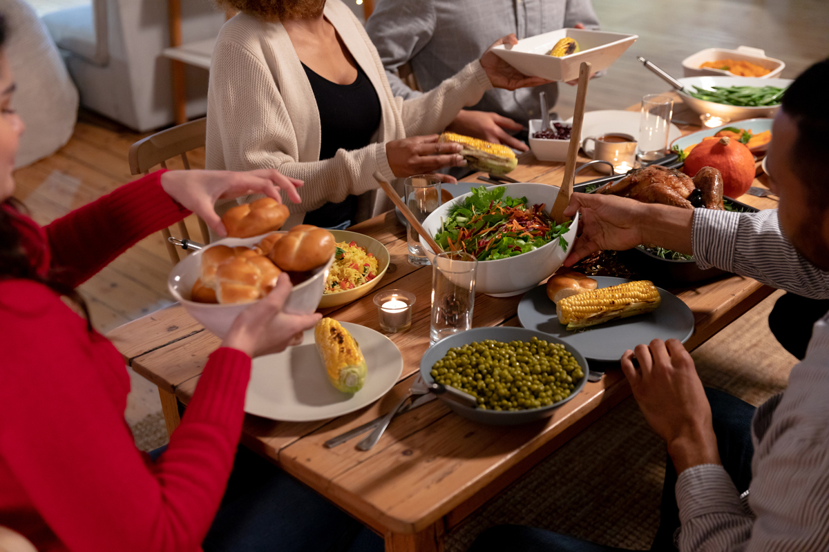 Family members pass bowls of food around a holiday table.