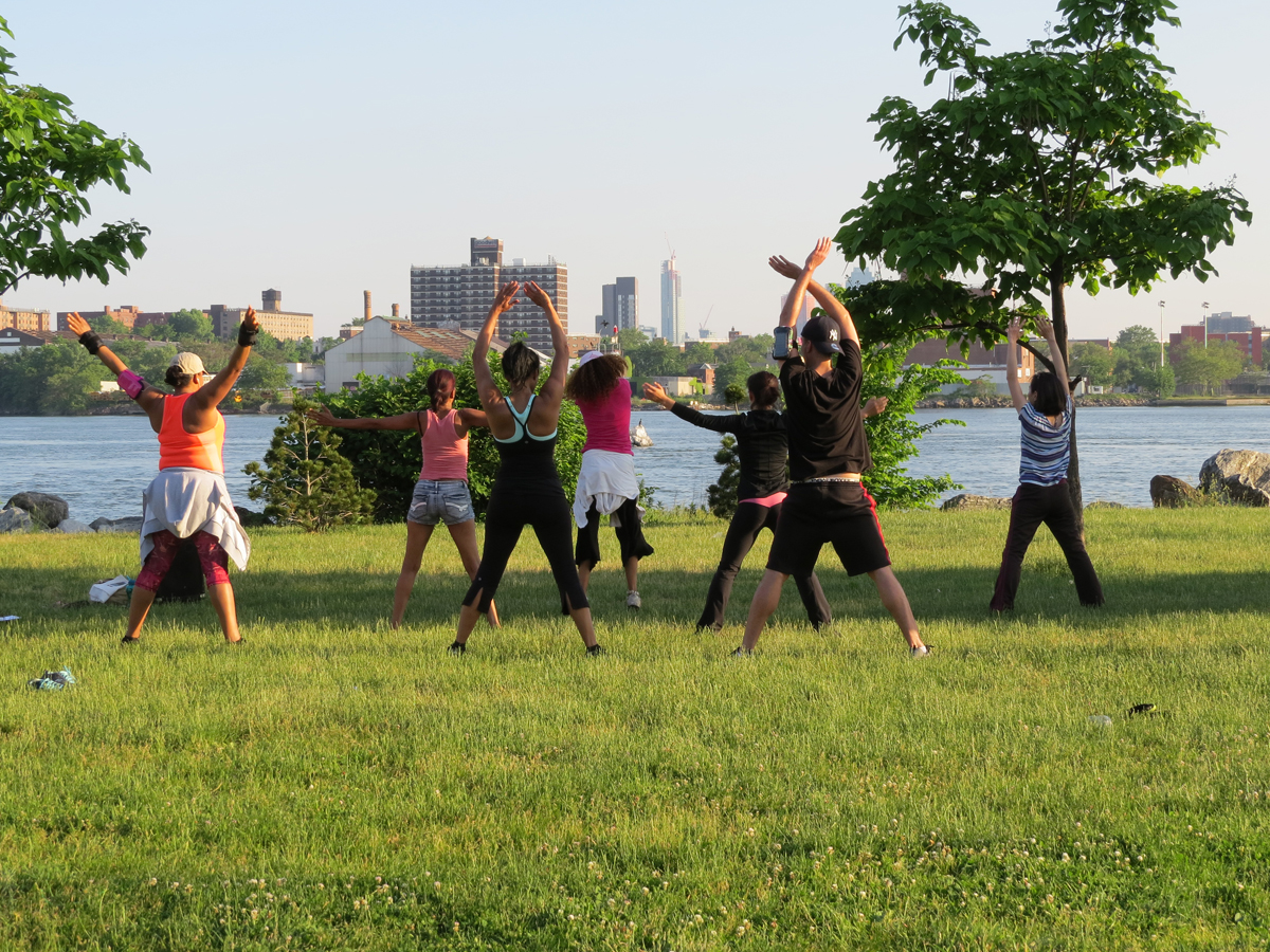 A group of people attend an outdoor exercise class at a park.