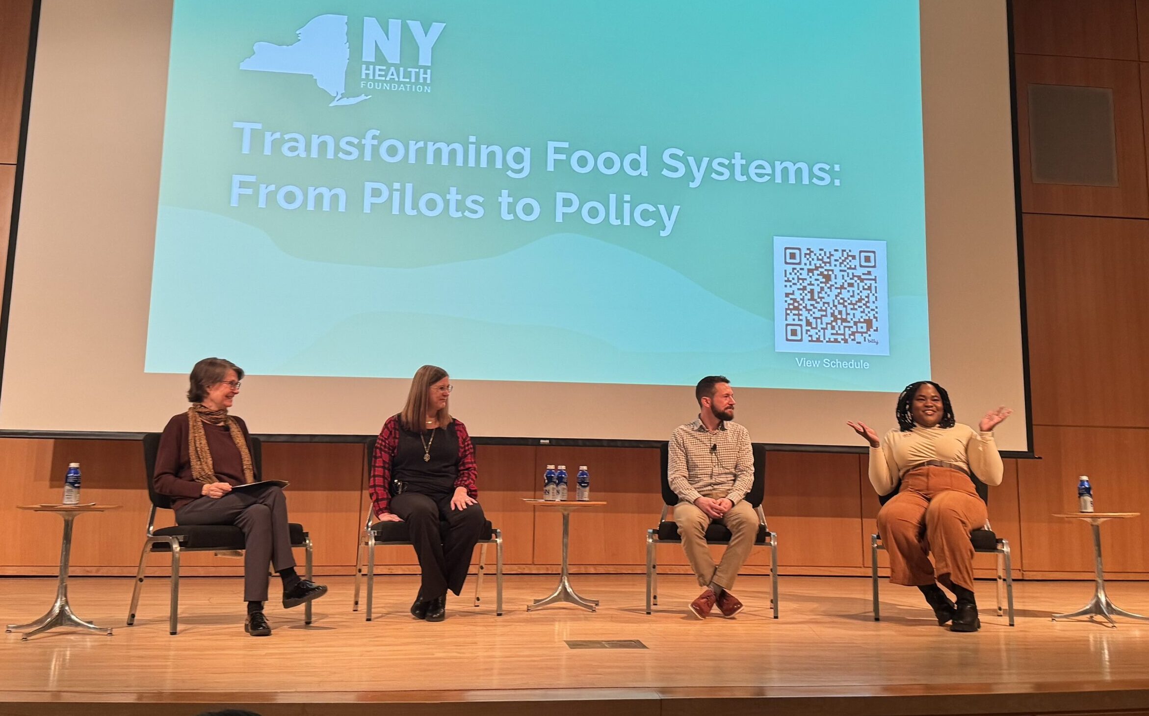 Four panelists sitting on a stage at the Transforming Food Systems Conference hosted by NYHealth.