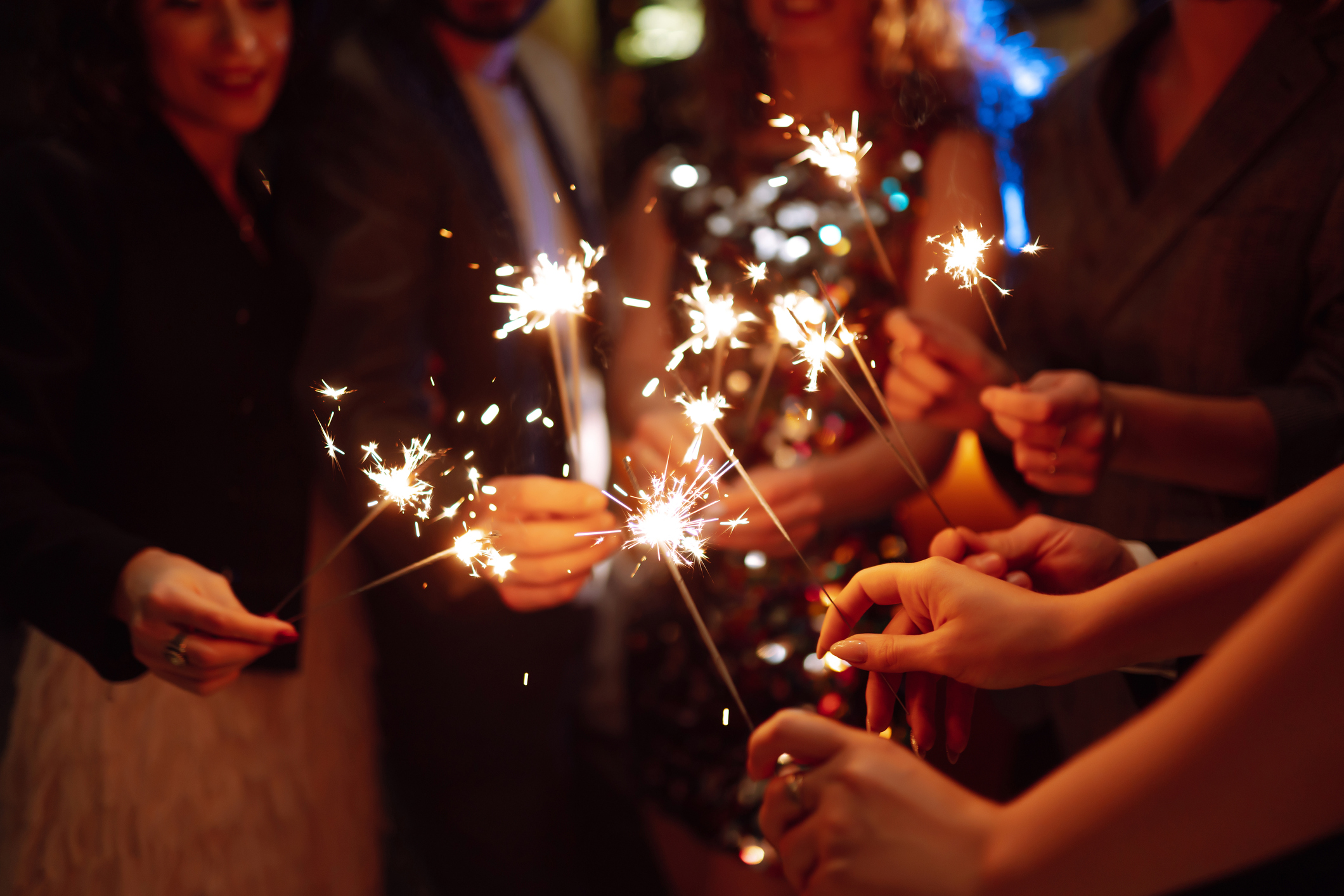 A group of people smiling and holding glowing sparklers.