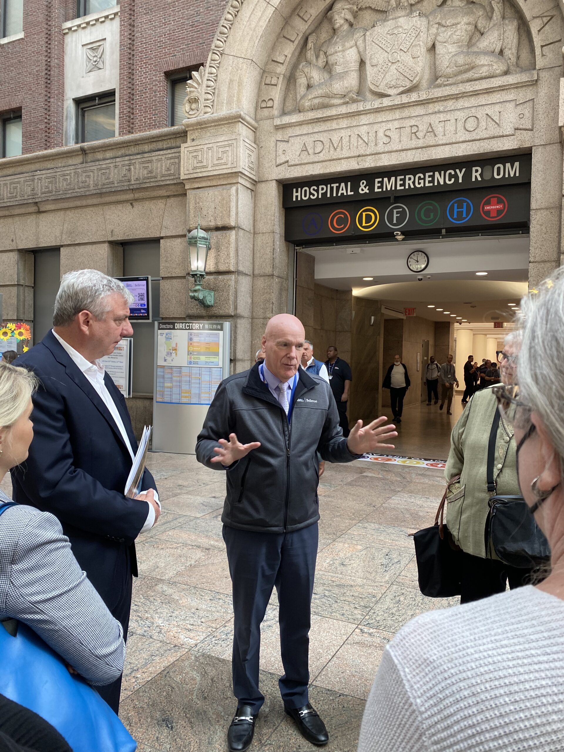 A group of people stand in the lobby of Bellevue Hospital while on a tour.